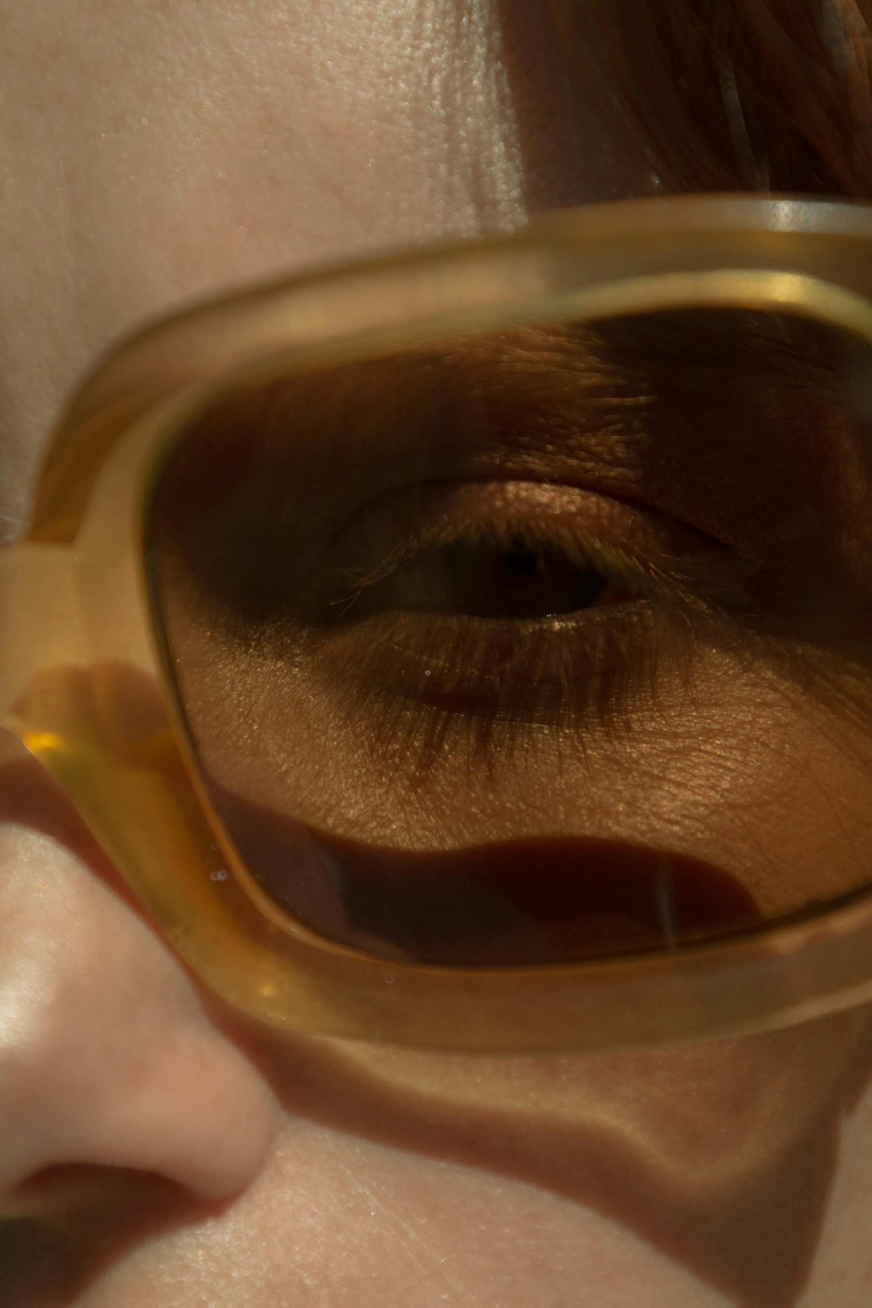 Close-up of a person's eye wearing fashionable sunglasses, capturing intimacy and style.